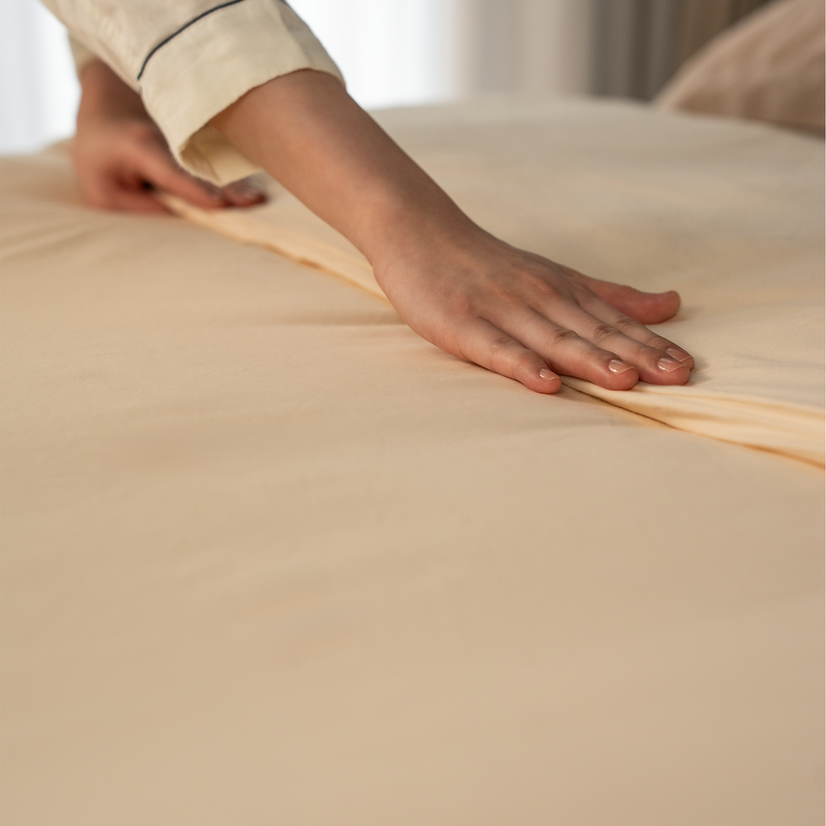 Smoothing the Dune Sand duvet cover flat on a bed