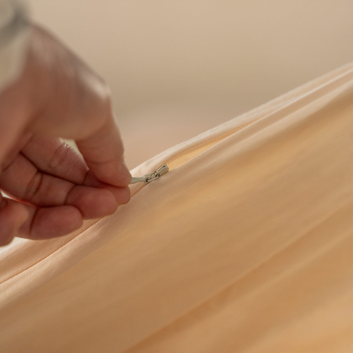 Hand closing the concealed zip on the Dune Sand duvet cover